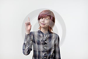 Portrait of unusual informal pretty woman with colorful hairstyle pointing with finger up.