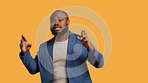 Portrait of upbeat man crossing fingers, making wish, studio background