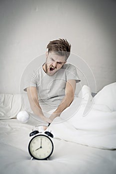 Portrait upset angry with baseball hit young man screaming at alarm clock on bedroom.