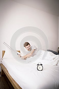 Portrait upset angry with baseball hit young man screaming at alarm clock on bedroom.