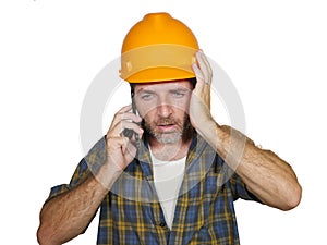 Portrait of upset construction worker or stressed contractor man in builder hat talking on mobile phone unhappy in stress messing
