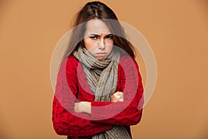 Portrait of upset freezing woman in red knitted sweater standing