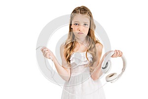 portrait of upset little girl with headphones looking at camera