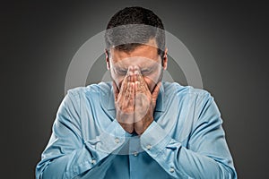 Portrait of upset man covering his face by hands