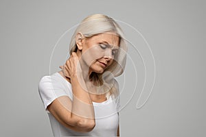 Portrait of upset mature woman suffering neck pain and strain