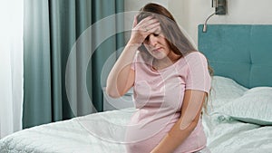 Portrait of upset pregnant woman feeling lonely and upset sitting on bed at home. Concept of maternal and pregnancy