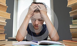 Portrait of upset schoolboy looking at textbook with homework