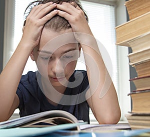 Portrait of upset schoolboy looking at textbook with homework