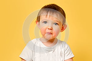 Portrait of an upset toddler baby with a surprised sad face on a studio