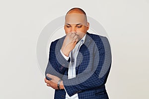 Portrait of an upset young African American businessman guy, looks tense and nervous with hands on lips, biting his nails. Anxiety