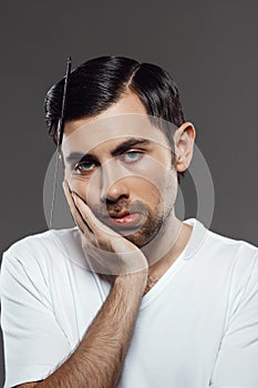 Portrait of upset young man with comb in tangled hair.