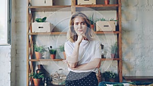 Portrait of upset young woman looking at camera and expressing negative emotions standing inside modern loft style