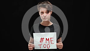 Portrait of upset young woman posing with Me too banner at black background. Sad Caucasian oppressed abused lady looking