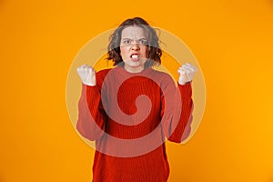 Portrait of uptight woman gesturing and yelling while standing isolated over yellow background