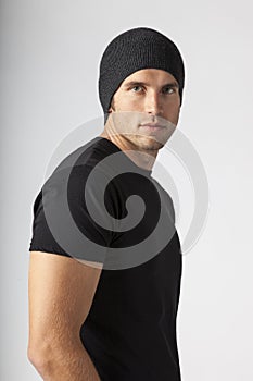 Portrait of urban young man wearing black t-shirt and knit hat. Men`s modern casual clothing fashions street styles. photo