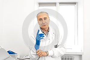 Portrait of a urologist doctor putting on medical gloves before examining a patient