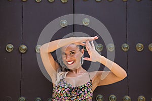 Portrait of very attractive young blonde woman showing time out with her hands on a background of a wooden door. The woman is