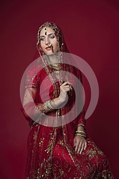 Portrait of very beautiful young Indian bride in luxurious bridal costume with makeup and heavy jewellery