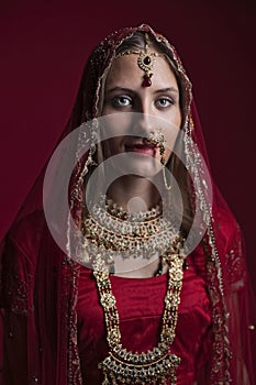 Portrait of very beautiful young Indian bride in luxurious bridal costume with makeup and heavy jewellery