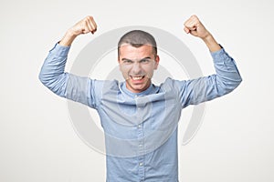 Portrait of very excited young hispanic man, celebrating victory with raised hands and screaming