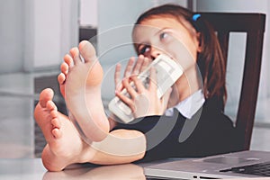 Portrait of very happy cute young business girl with bare feet on the table and counts money profit. Selective focus on feet