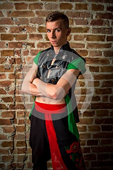 portrait of a very muscular Caucasian male model dancer in national costume against a brick wall