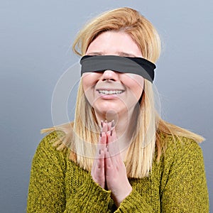 Portrait of victim of abuse and domestic violence blindfolded against gray background