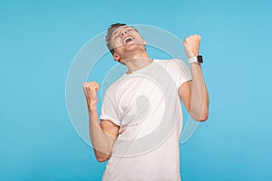 Portrait of victorious ecstatic man in casual white t-shirt screaming yes I`m winner