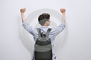 Portrait of victorious man looking up while standing on white background and celebrating with fists in the air