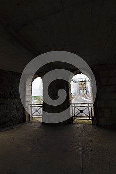 Portrait view looking out onto the Grade I Listed Menai Suspension Bridge from an undercover vantage point, Gwynedd, North Wales