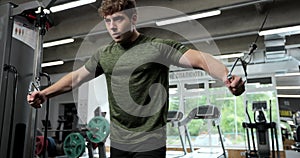 Portrait view of the man training arms with trx fitness strips in gym. Sport man with TRX straps spending time in the