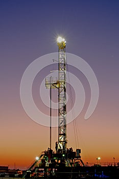 Portrait view of an oil drilling rig at sunrise.