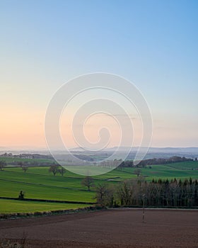 Portrait view of rolling english countryside with blue sky and green fields