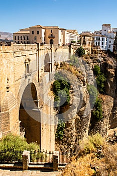 Portrait view of Ronda and its spectacular deep gorge, with a massive stone bridge and arches, Spain