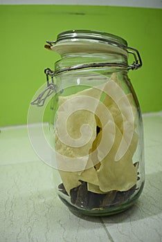 Portrait view a transparent jar inside fry poppadum in green and white background