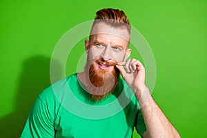 Portrait of virile guy with red beard wear stylish t-shirt look at discount in barbershop empty space isolated on green