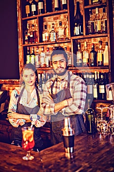 Portrait of waiter and waitress standing with arms crossed at counter