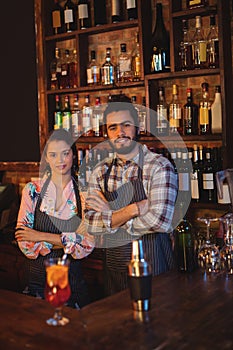 Portrait of waiter and waitress standing with arms crossed at counter