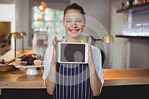 Portrait of waitress holding digital tablet at counter