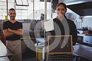 Portrait of waitress with open sign at cafe