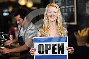 Portrait of waitress showing open sign