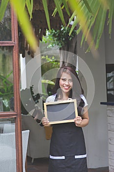 Waitress standing at the front of a cafe inviting people to come