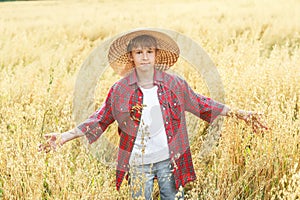 Portrait of walking teenage boy in yellow wide-brimmed natural straw hat