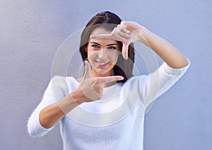 Portrait, wall and woman with finger frame, smile and focus for creative fashion photography. Perspective, hand gesture