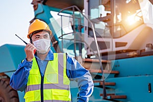 Portrait of warehouse asian man worker driver truck driver crane lifting up container with safety equipment standing in front of
