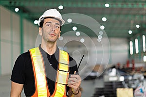 portrait warehouse manager supervisor, safety officer male standing indoor with radio to control operate factory cargo