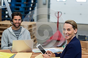 Portrait of warehouse managers using digital tablet and laptop