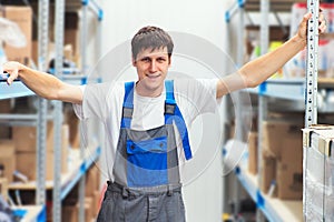 Portrait of warehouse worker against background of racks with shelves.