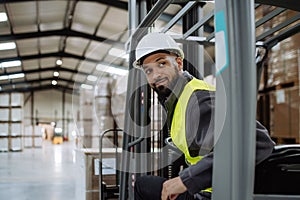 Portrait of warehouse worker driving forklift. Warehouse worker preparing products for shipmennt, delivery, checking