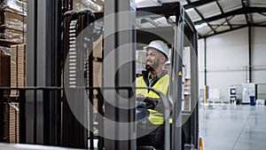 Portrait of warehouse worker driving forklift. Warehouse worker preparing products for shipmennt, delivery, checking